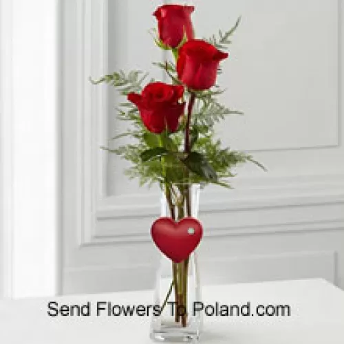 3 roses rouges dans un vase en verre avec un petit cœur attaché
