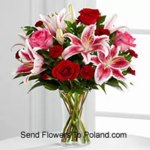 Roses rouges et roses avec des lys roses et des remplisseurs saisonniers dans un vase en verre